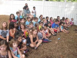 Group of children and adults sitting on the ground outdoors