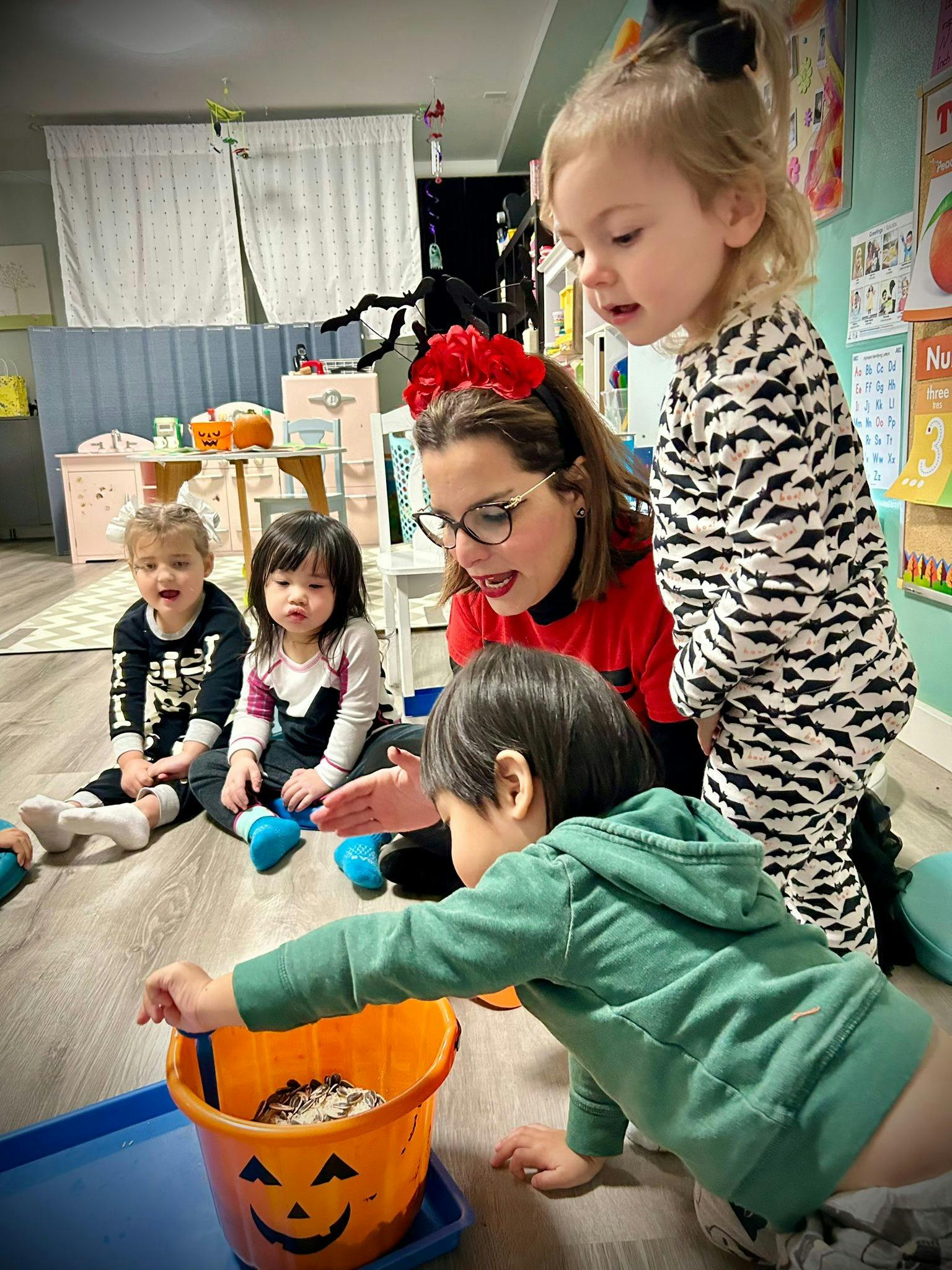 Adult and children gathered around a jack-o'-lantern bucket