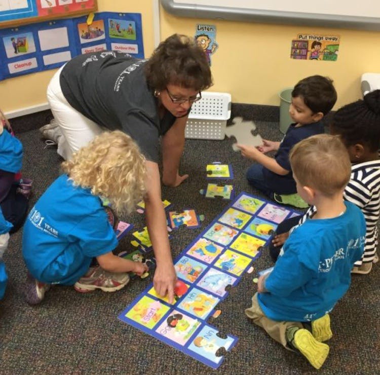 Adult and children playing with a large floor puzzle