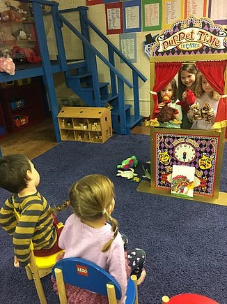 Children watching a puppet show in a classroom
