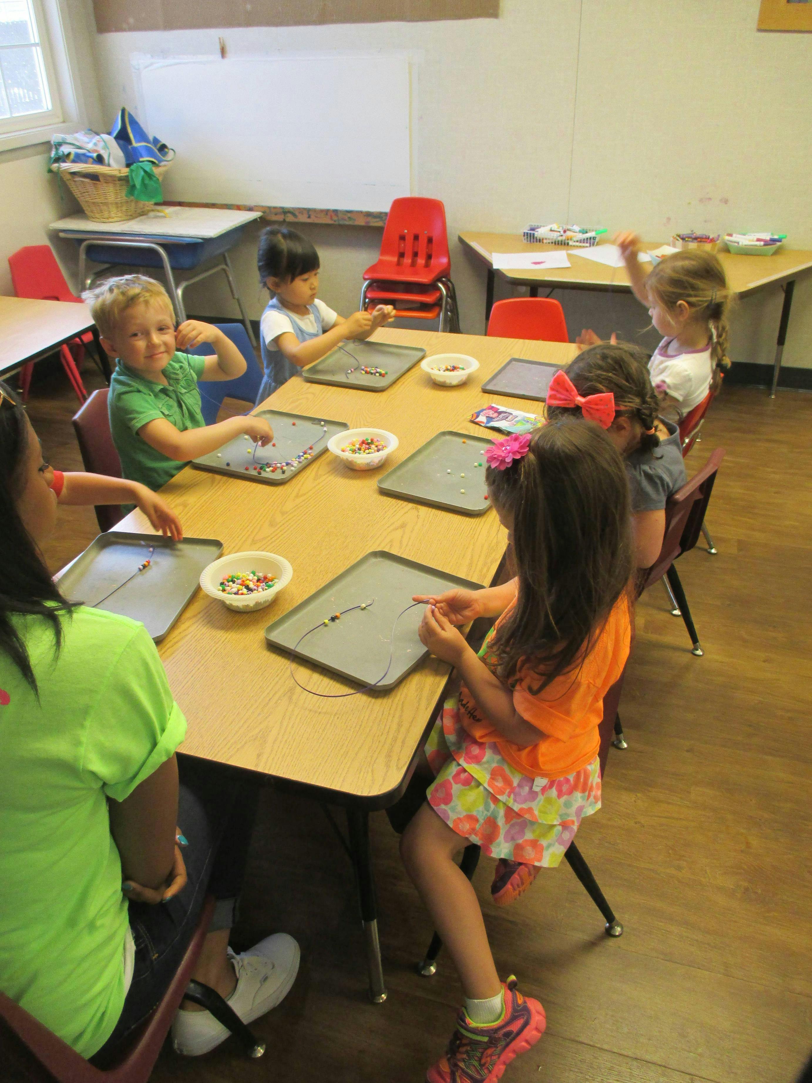 Children sitting at a table making crafts with beads
