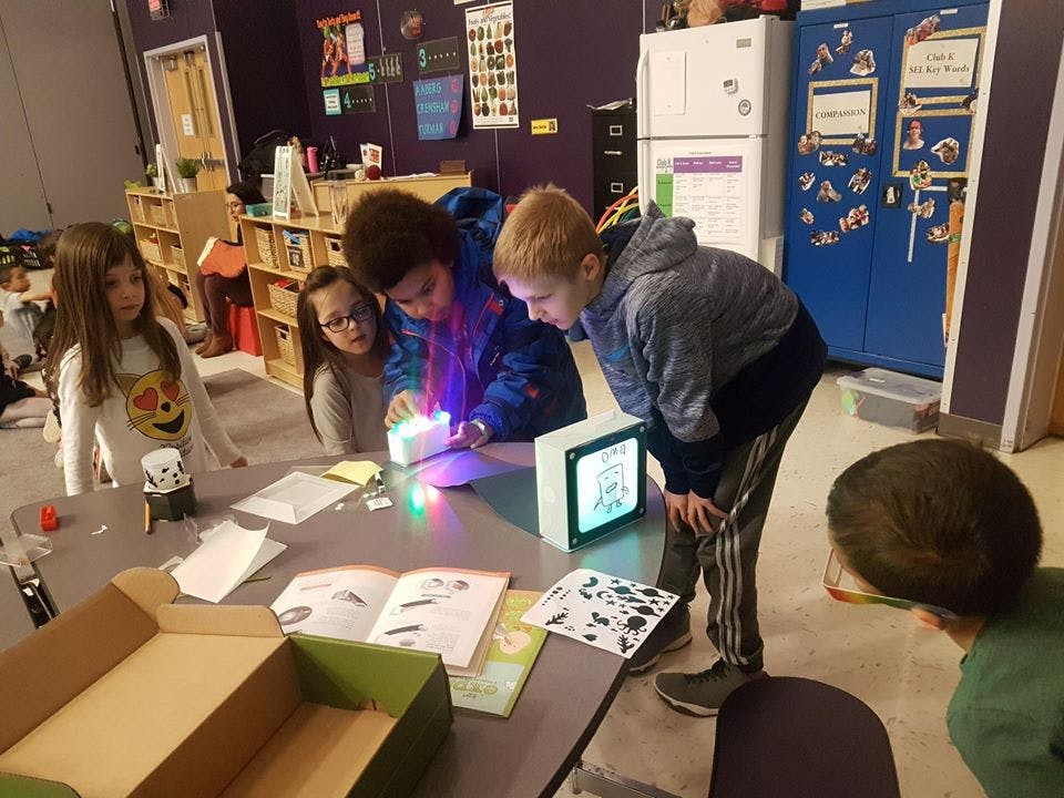 Children gathered around a table looking at a glowing device