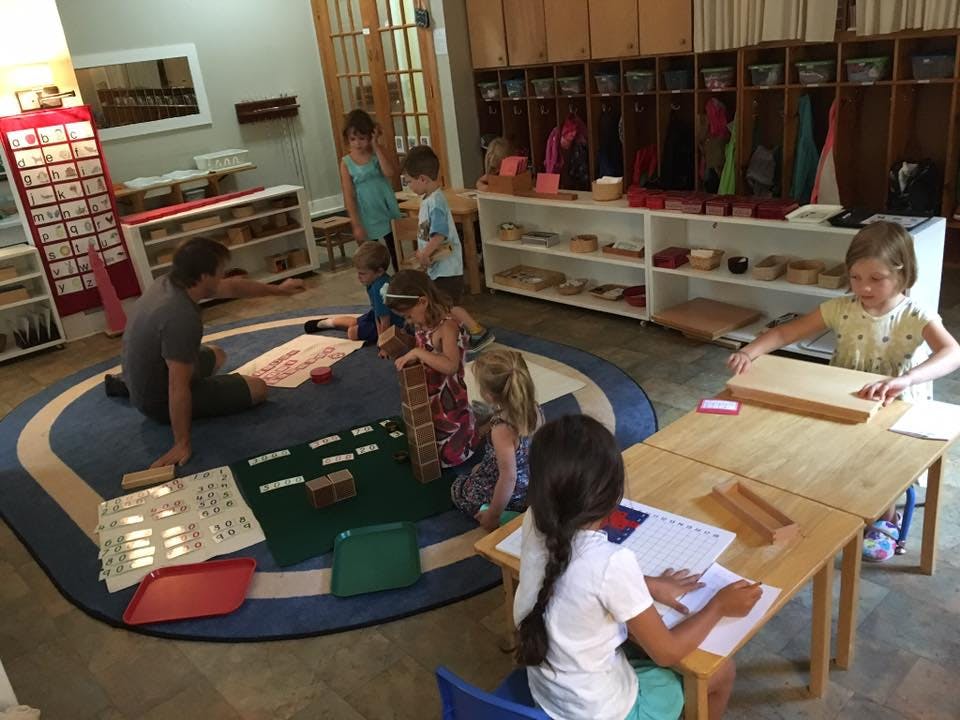 Adult and children engaged in various activities in a classroom