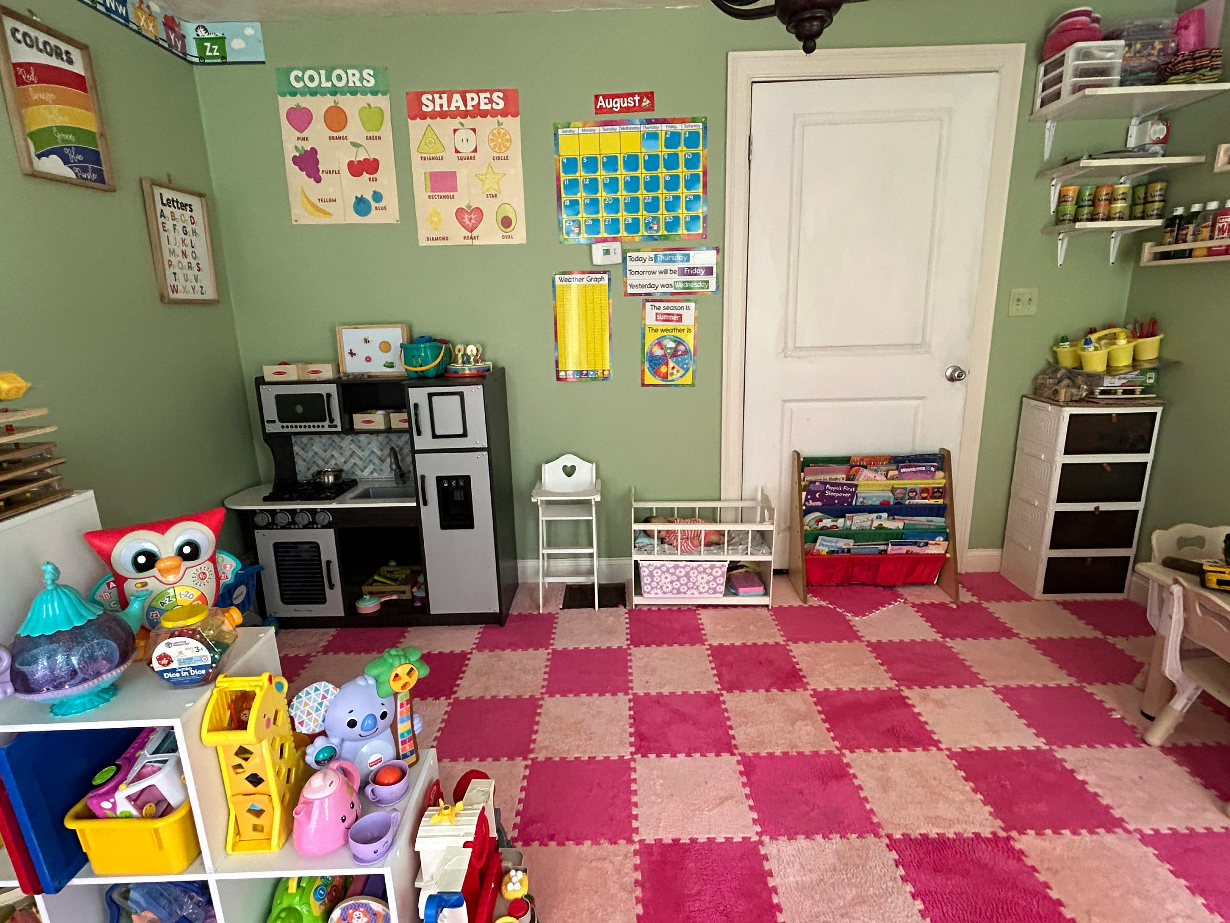 Playroom with toy kitchen, shelves of toys, and pink checkered floor