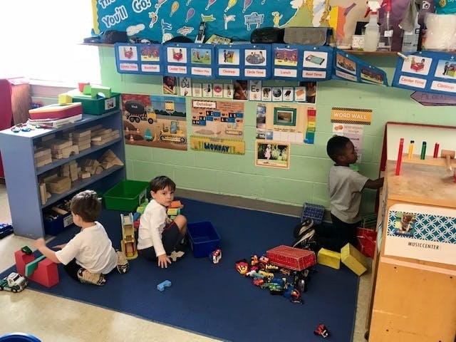 Three children playing with toys in a classroom