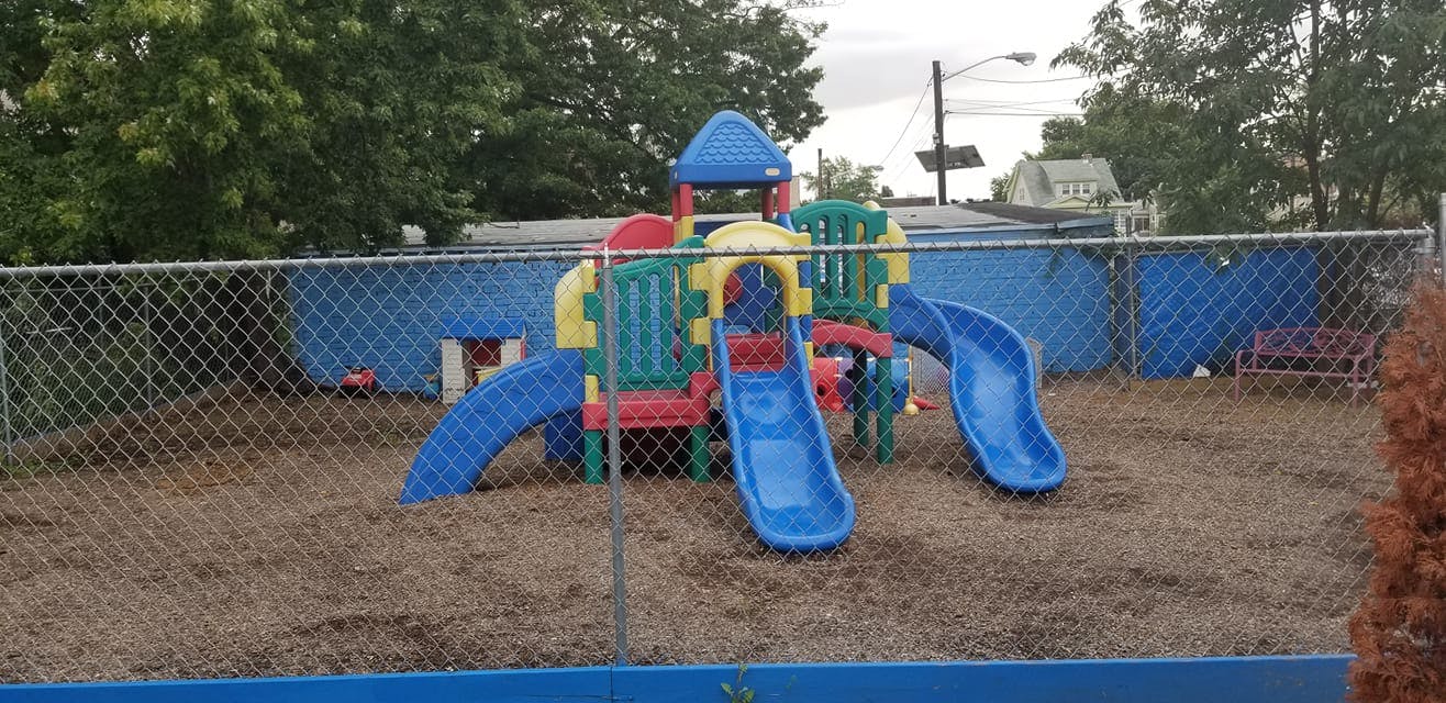 Playground with colorful slides and climbing structure behind a chain-link fence