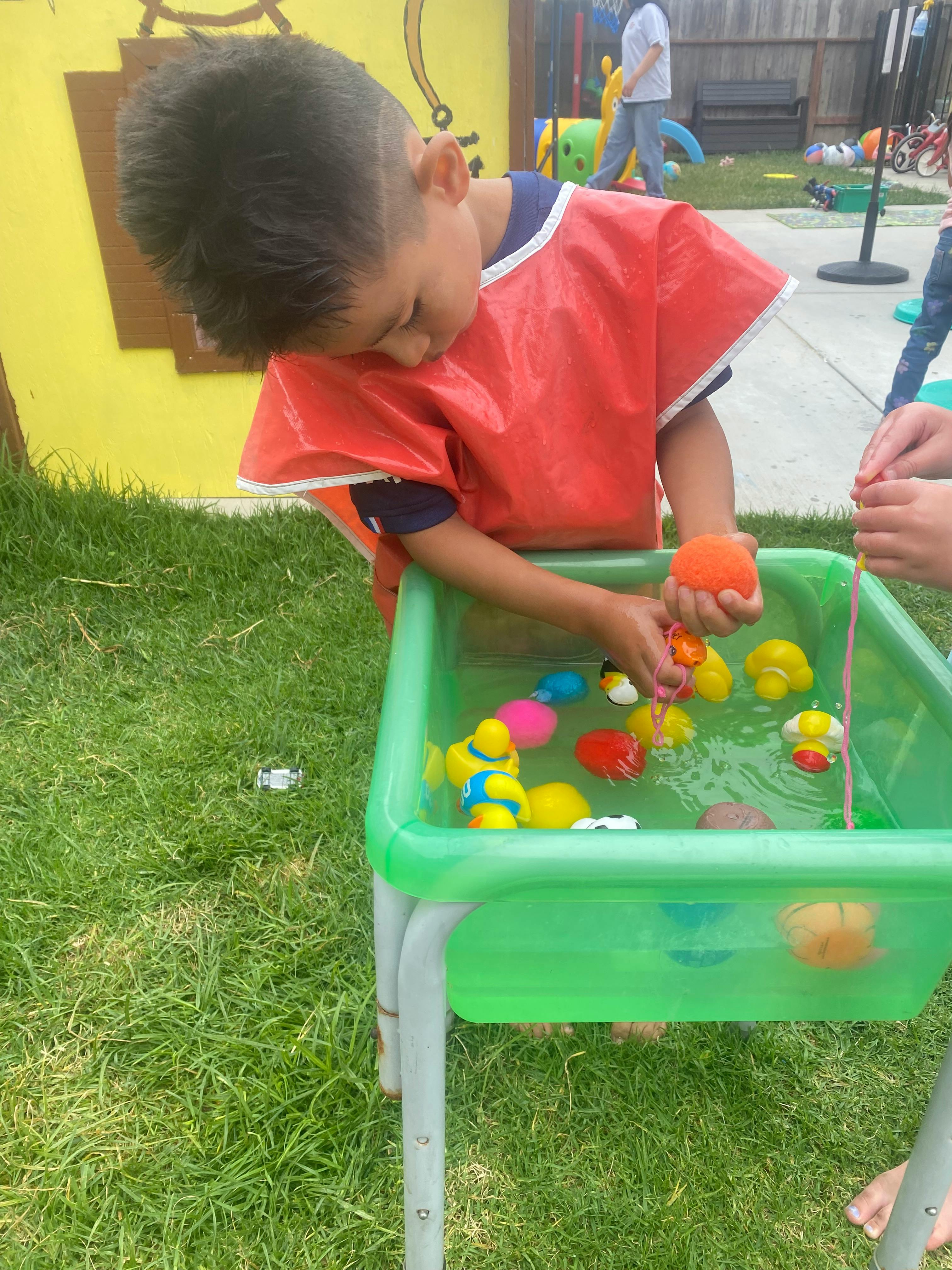 Child playing with toys in a water table