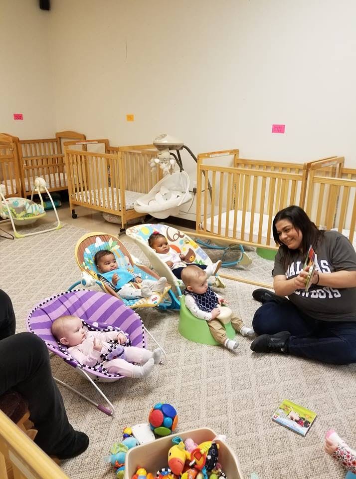 Person sitting on floor with multiple babies in bouncers and seats