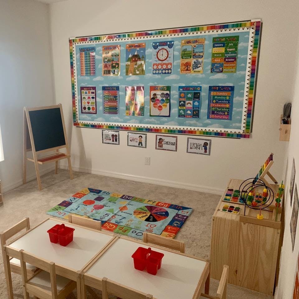 Classroom with a large bulletin board, small tables, and a rug