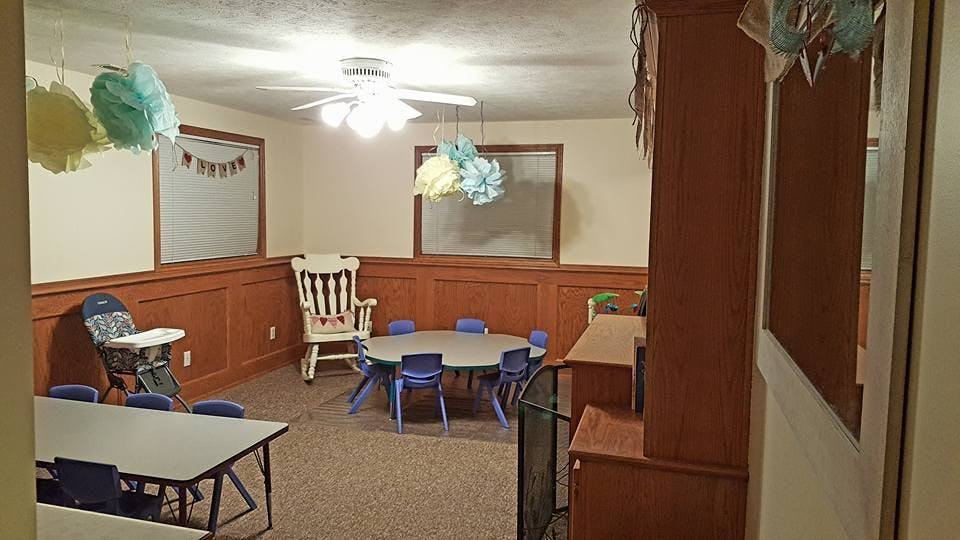 Room with small tables and chairs, a high chair, and ceiling fan