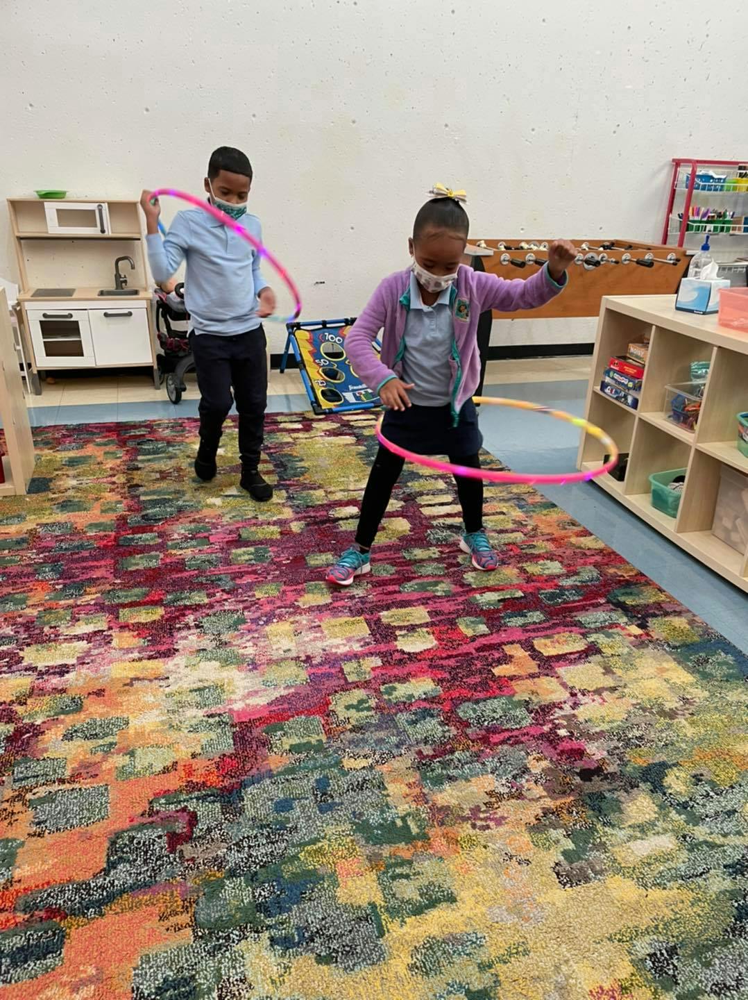Two children hula hooping indoors