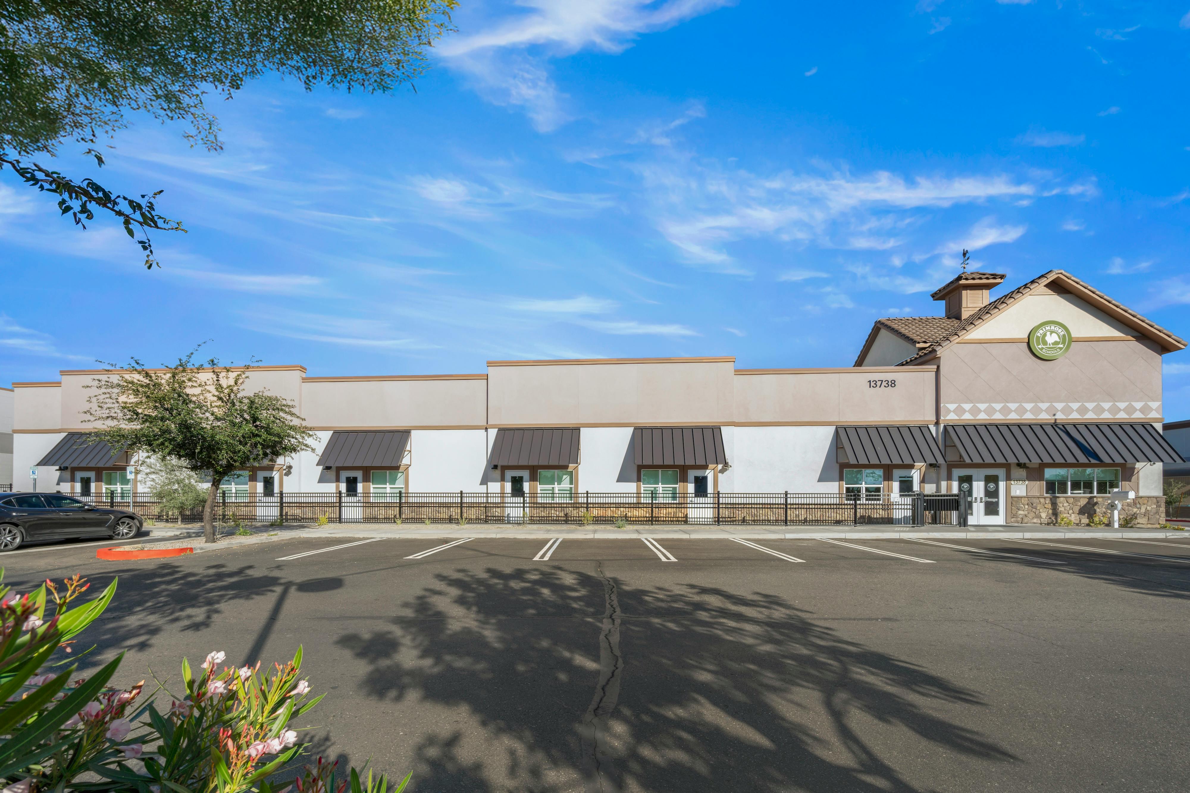 A beige and white building with dark awnings and a sign for Primrose Schools