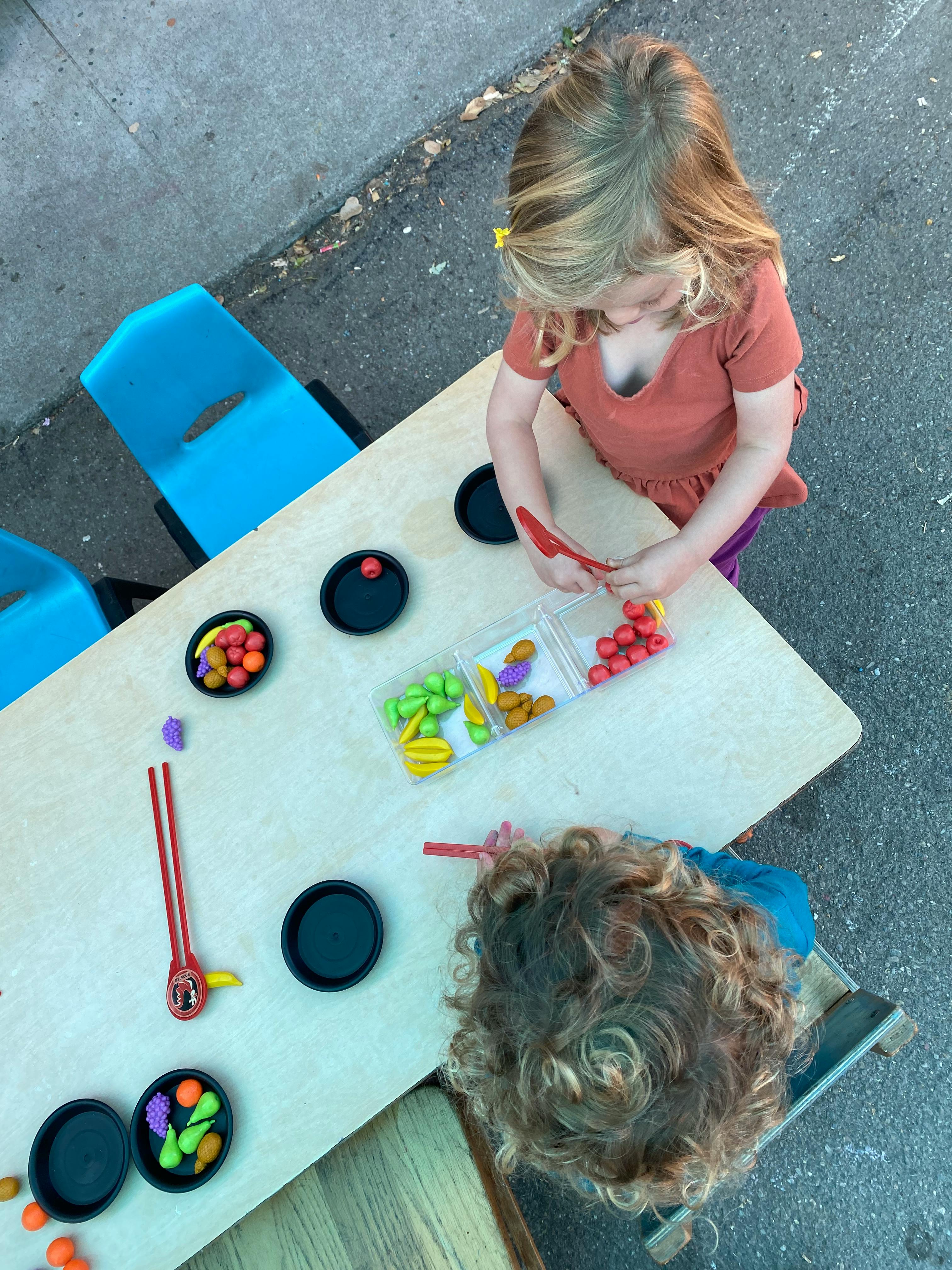 Two children playing with colorful sorting toys at a table