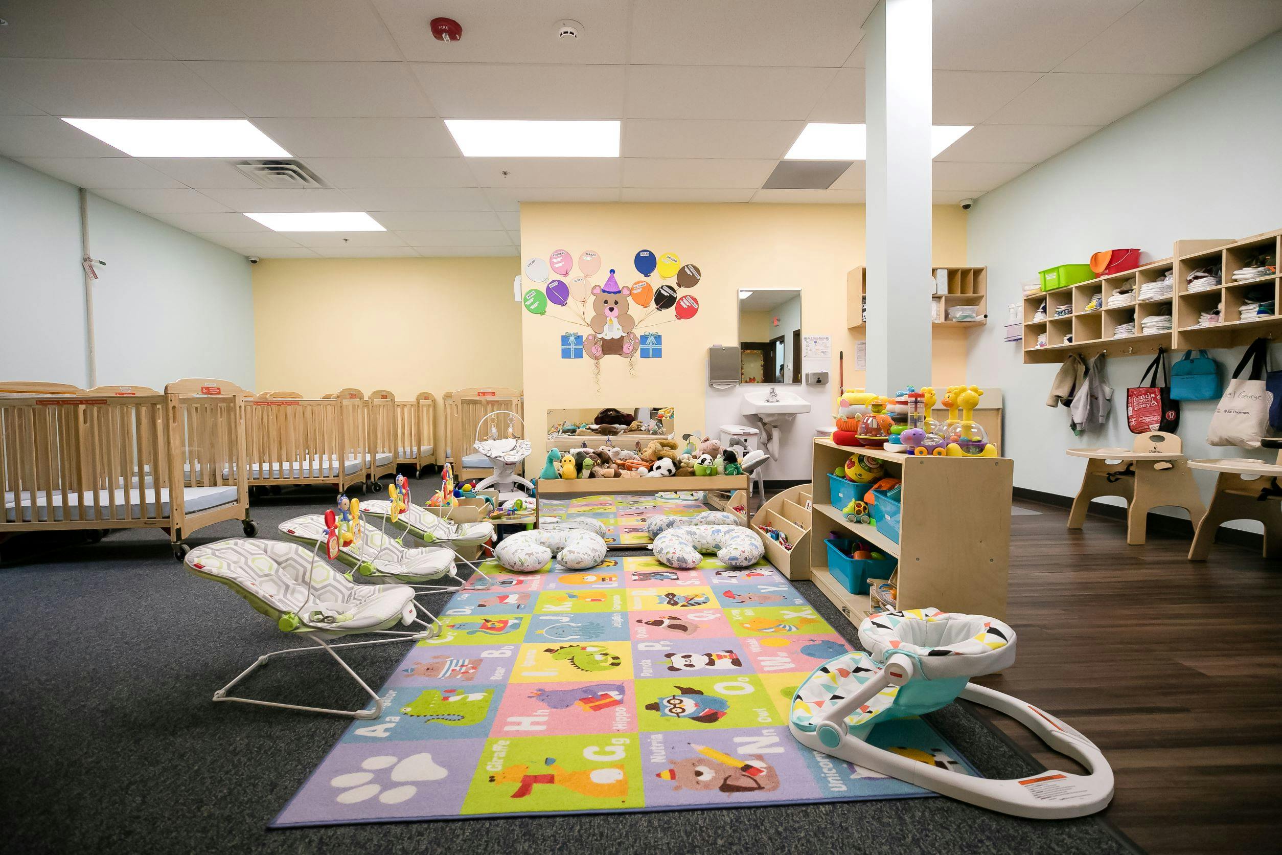 Infant room with cribs, play mat, and baby bouncers