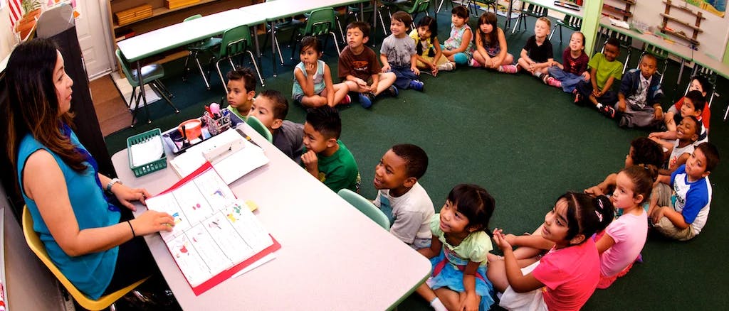 Person teaching a group of children sitting in a circle in a classroom