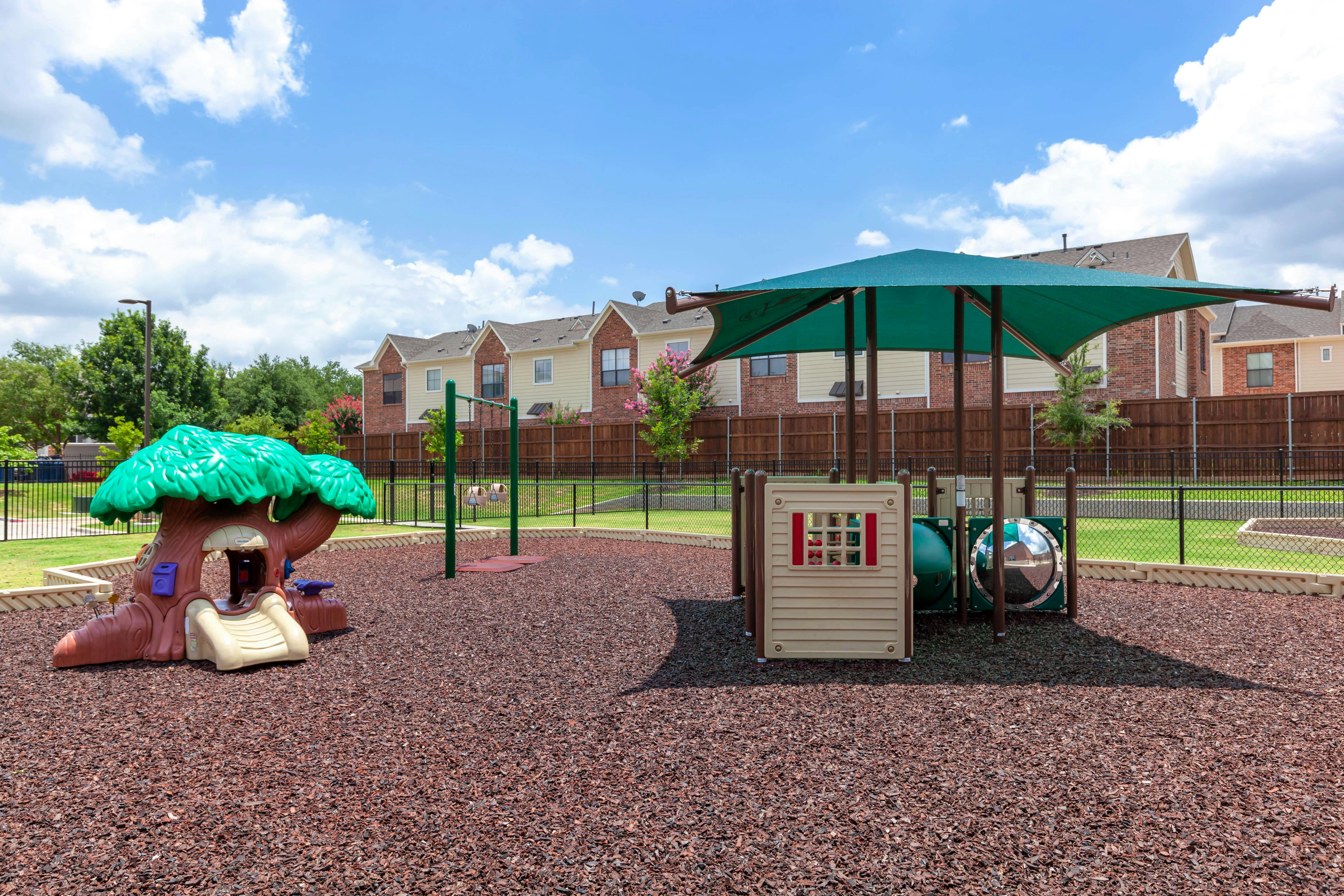 Playground with swings, a tree-shaped slide, and shaded play equipment