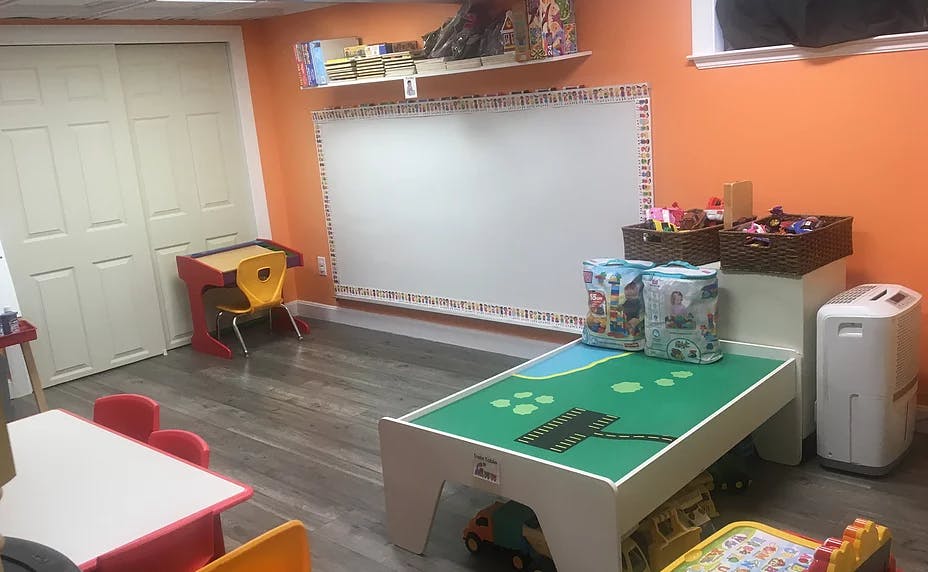 Playroom with a whiteboard, small tables, and a play table with building blocks