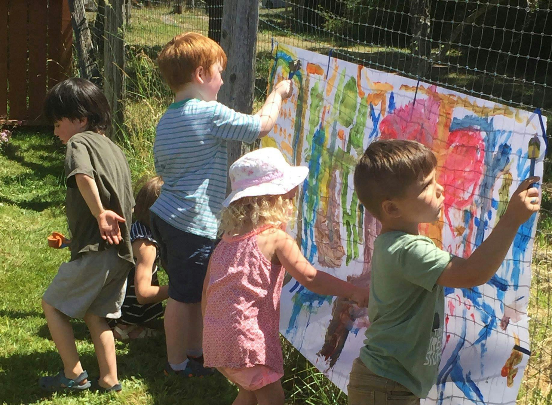 Children painting on a large canvas outdoors