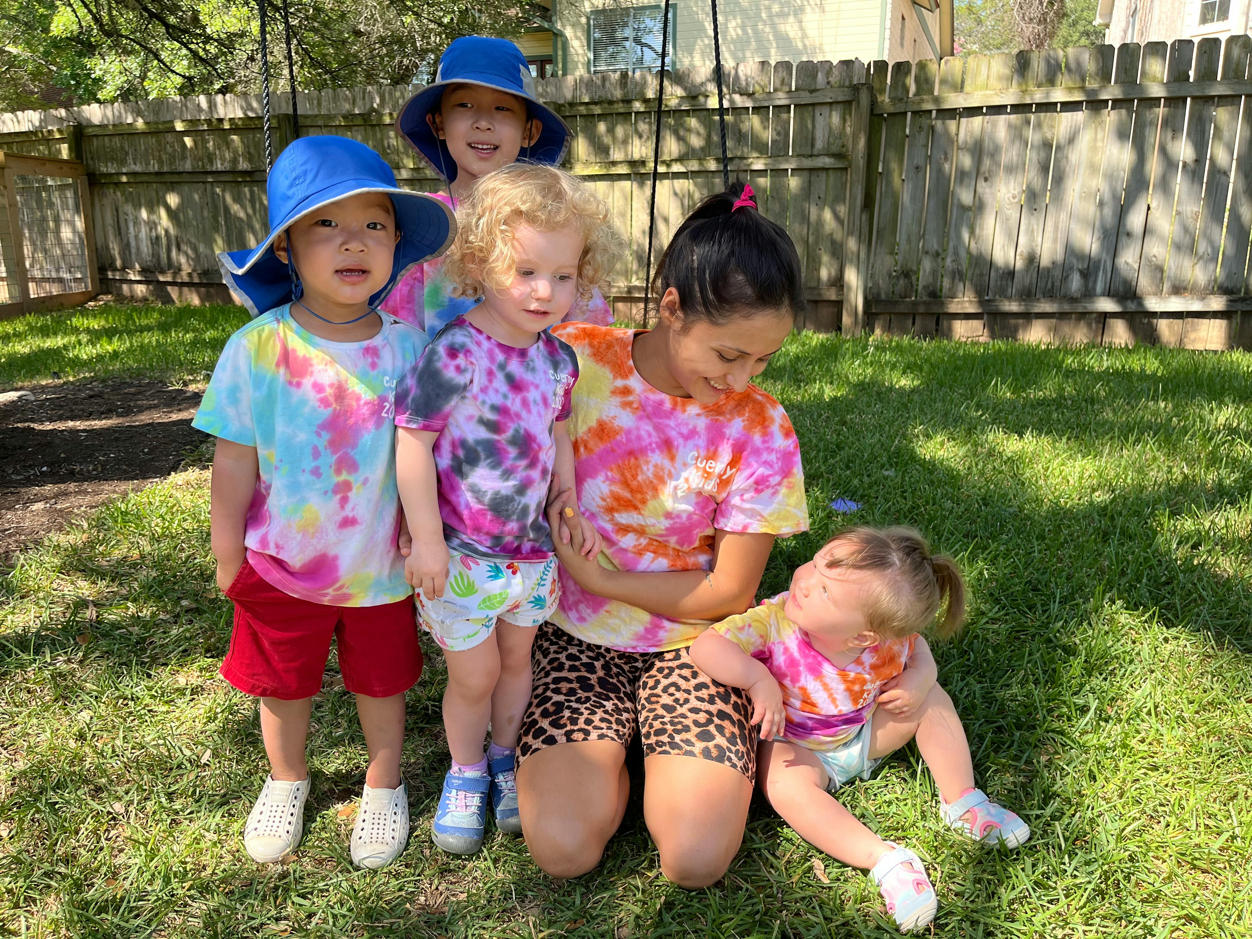 Five children and one adult in tie-dye shirts on grass