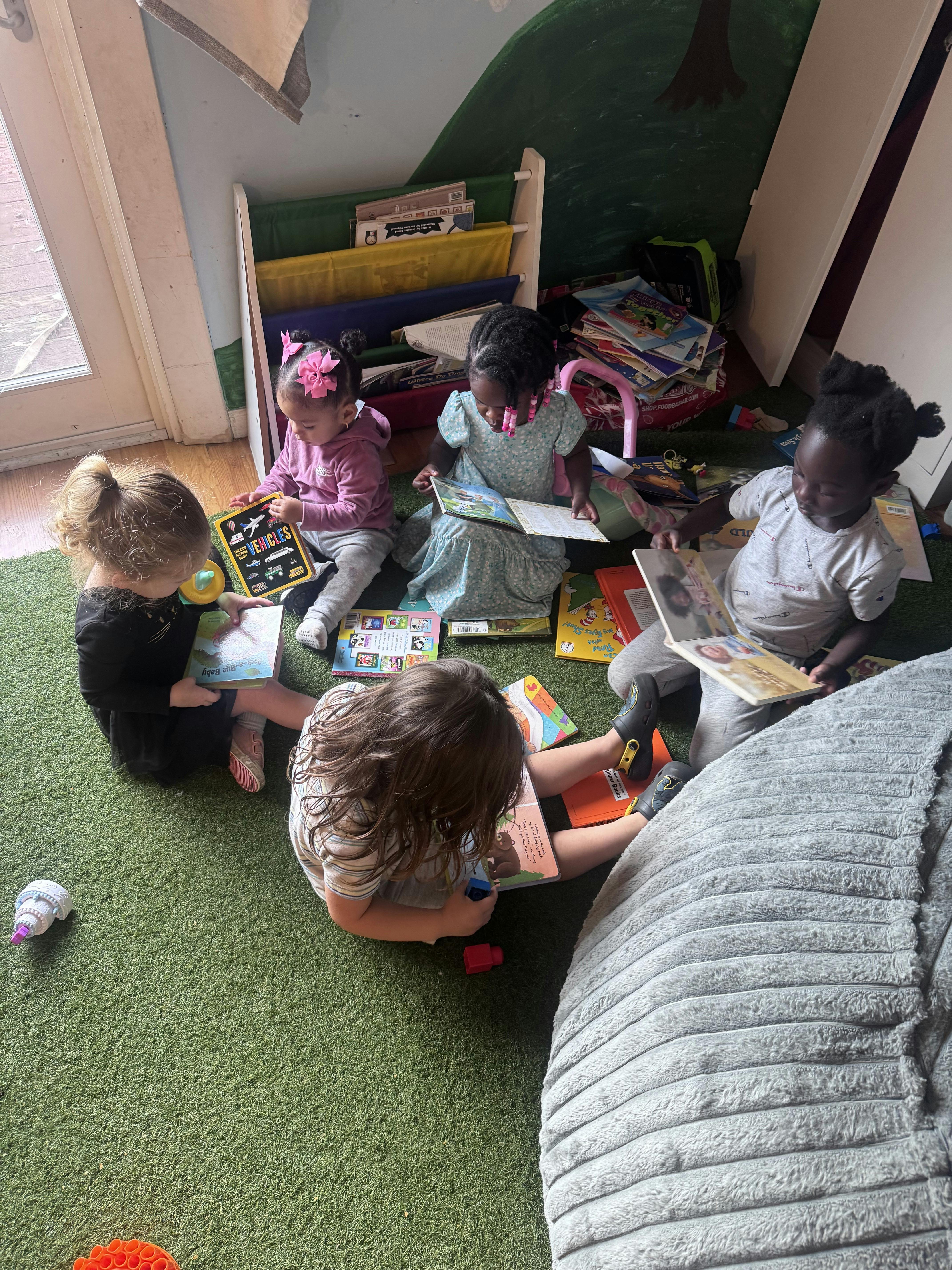 Children sitting on a green rug reading books