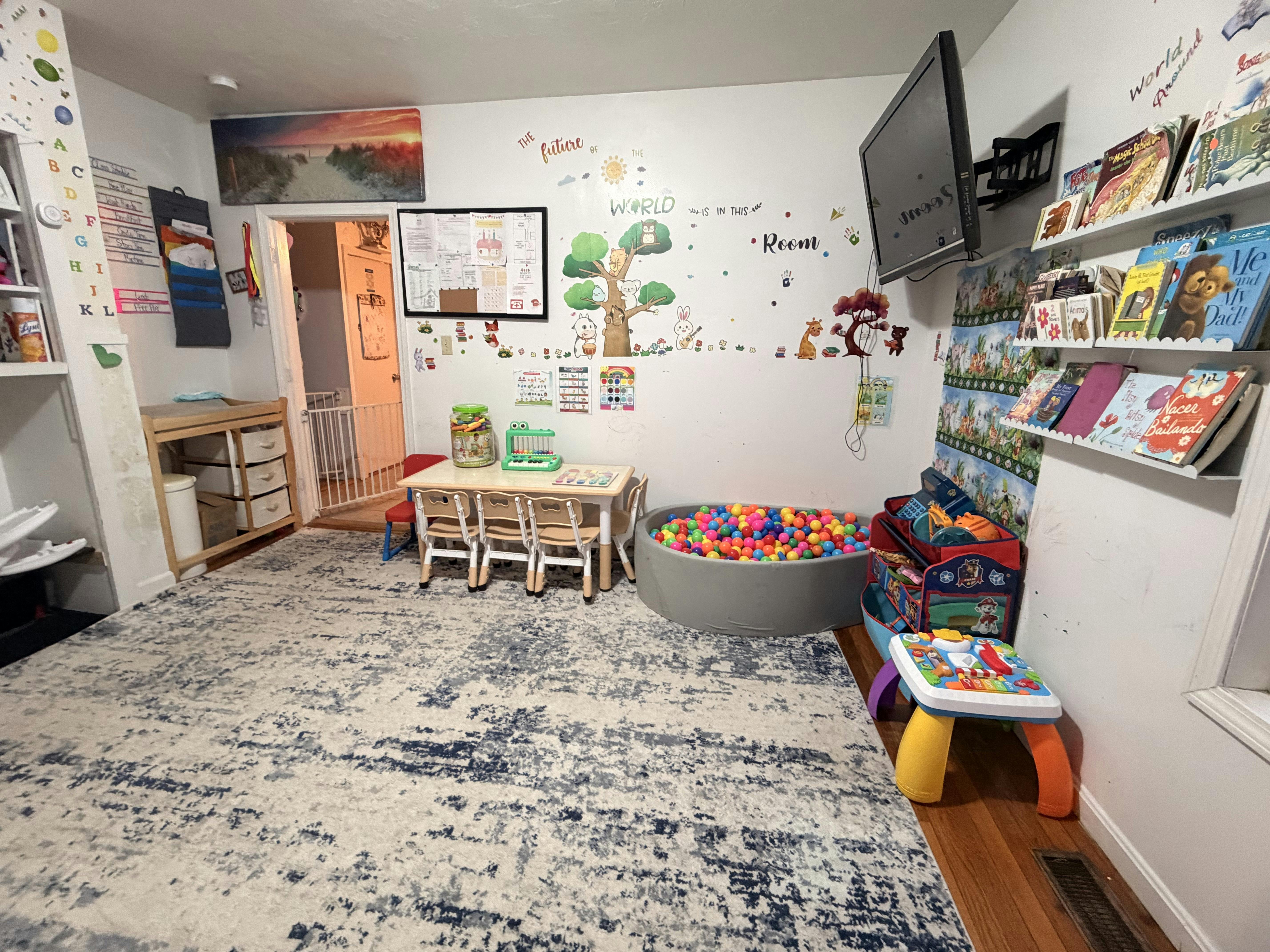 Playroom with a small table and chairs, a ball pit, book shelves, and wall decals