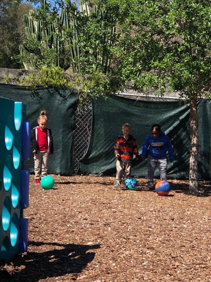 Three children playing with balls outdoors