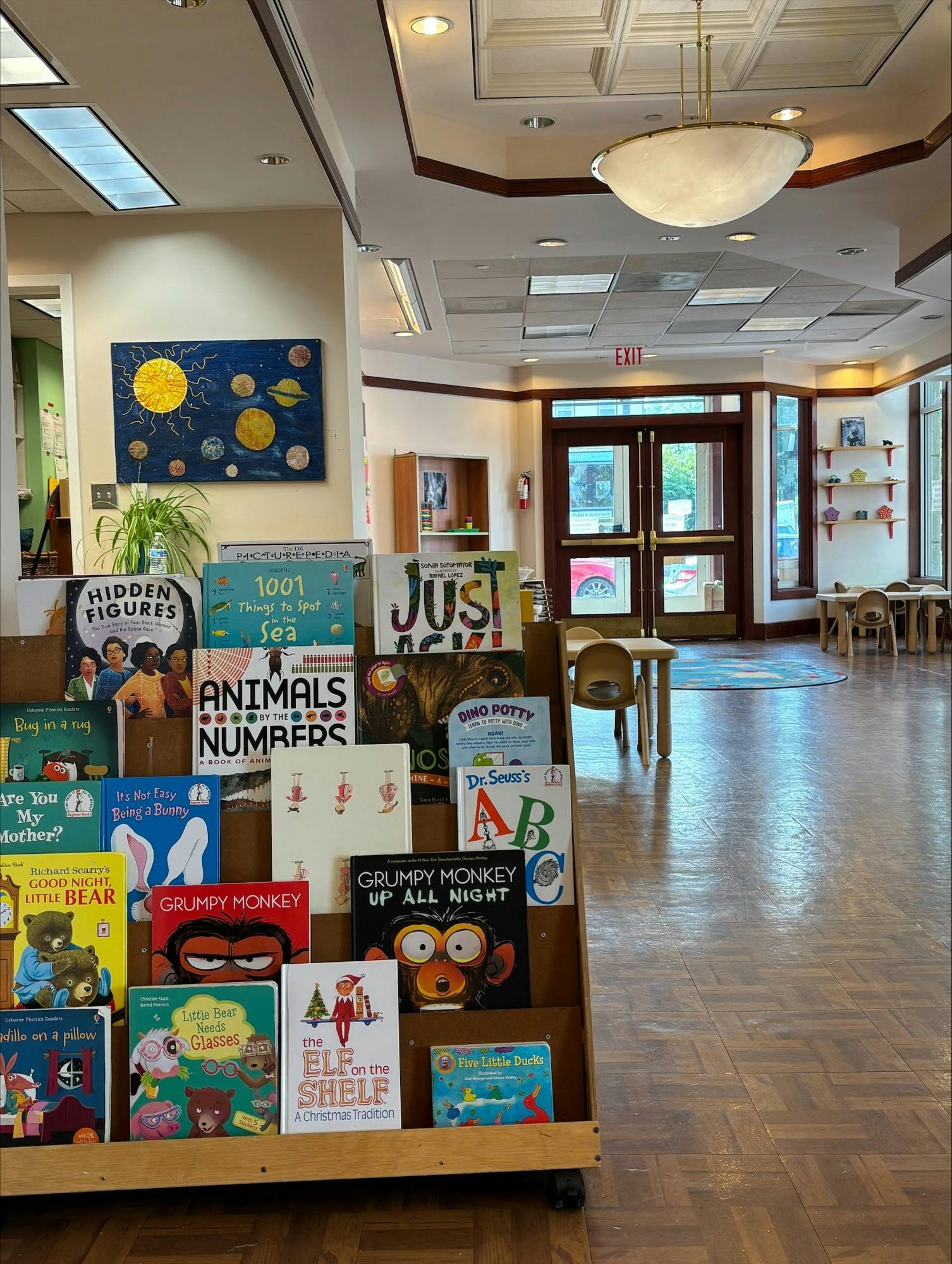 Children's books displayed on a wooden shelf in a room