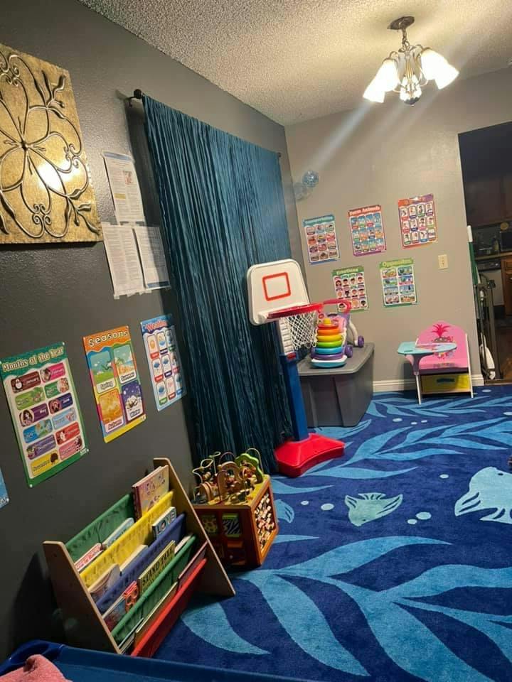 Playroom with a blue rug, small basketball hoop, and a bookshelf