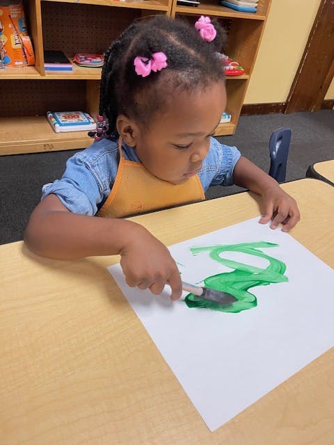 child painting with a palette knife in a classroom