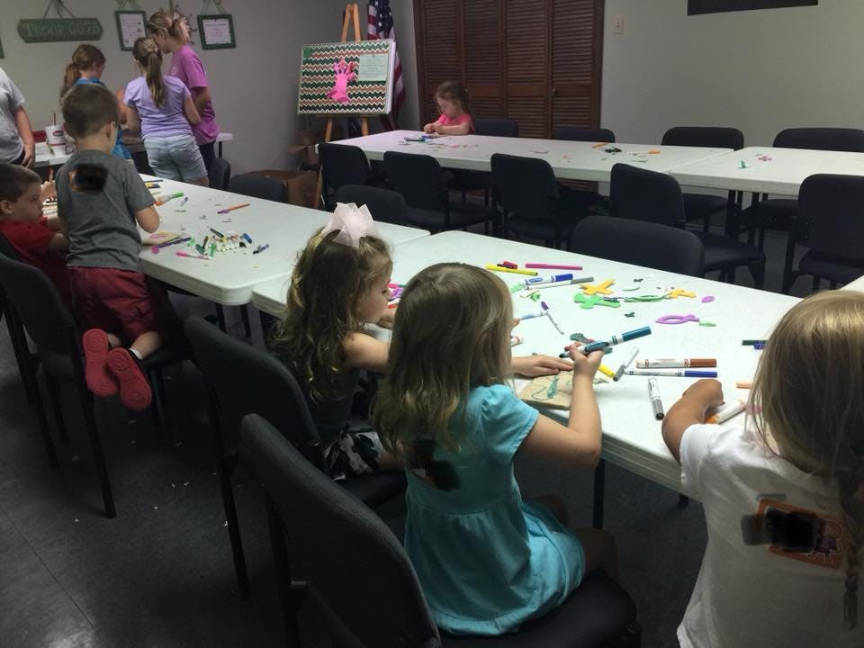 Children sitting at tables drawing with markers