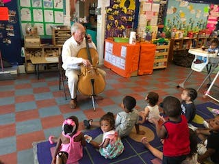 Person playing cello for children in a classroom