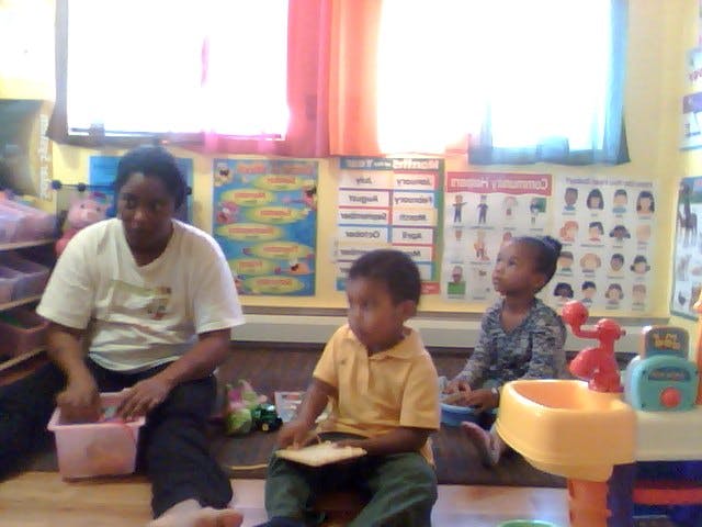 Person and two children sitting on the floor in a classroom