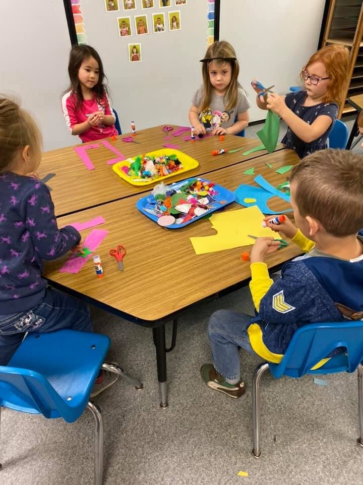 Children doing crafts at a table in a classroom