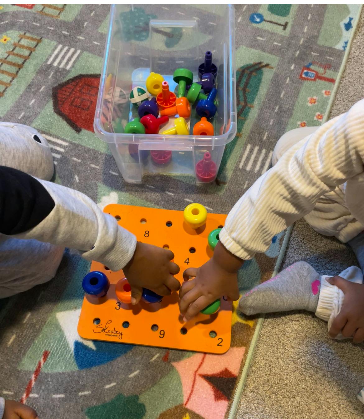 People playing with a numbered peg board and colorful plastic shapes