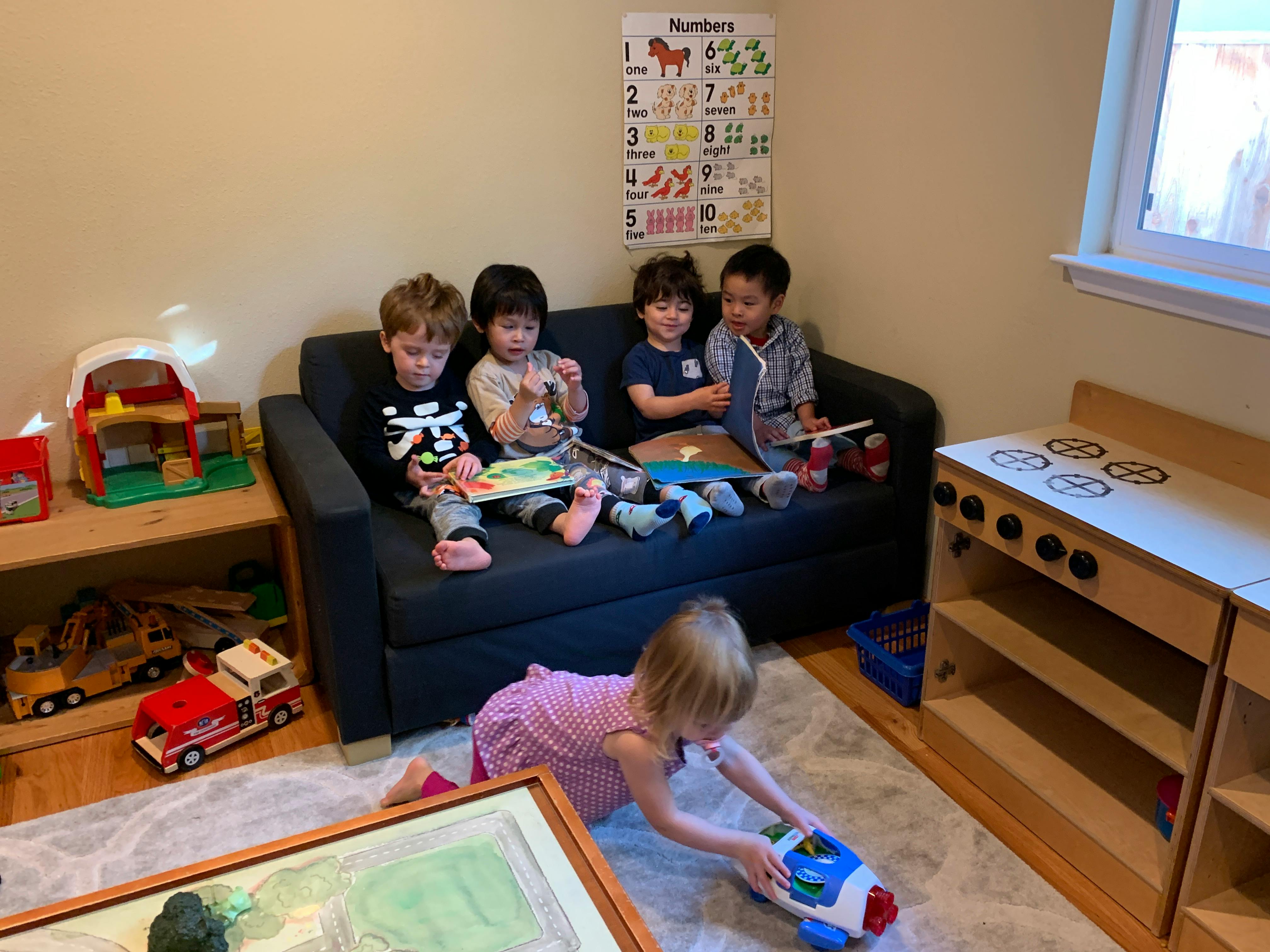 Children playing in a room, some on a couch and one on the floor