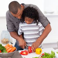Adult and child cutting vegetables in a kitchen