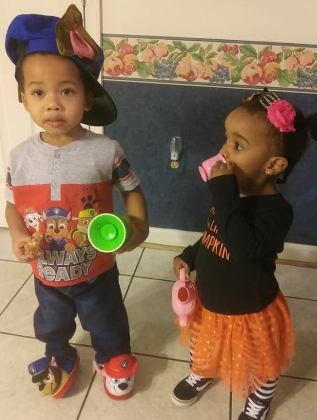 Child in Paw Patrol shirt holding green cup, child drinking from pink cup
