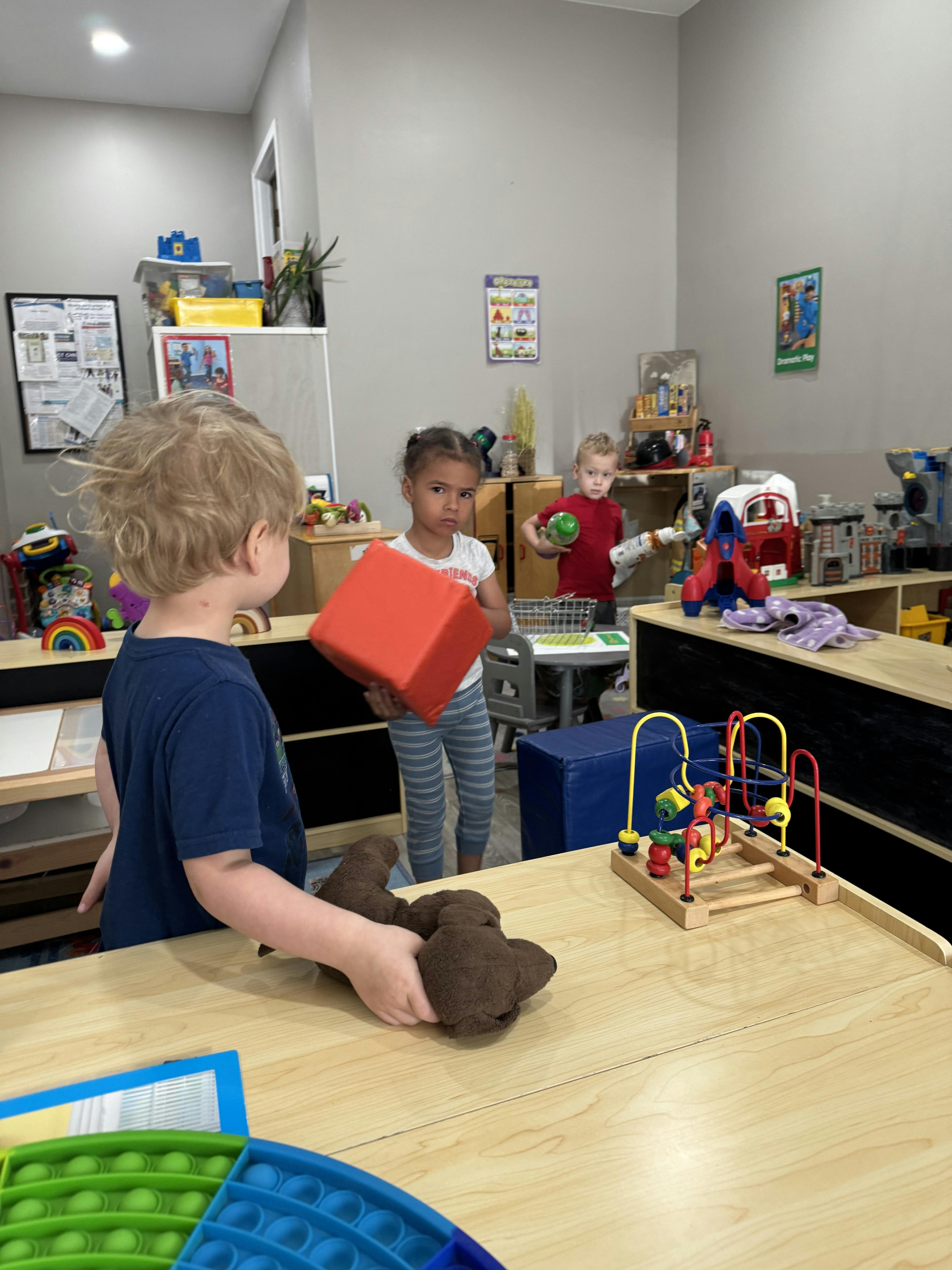 Three children playing with toys in a classroom