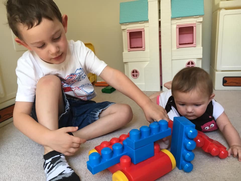 Child and baby playing with colorful building blocks on the floor