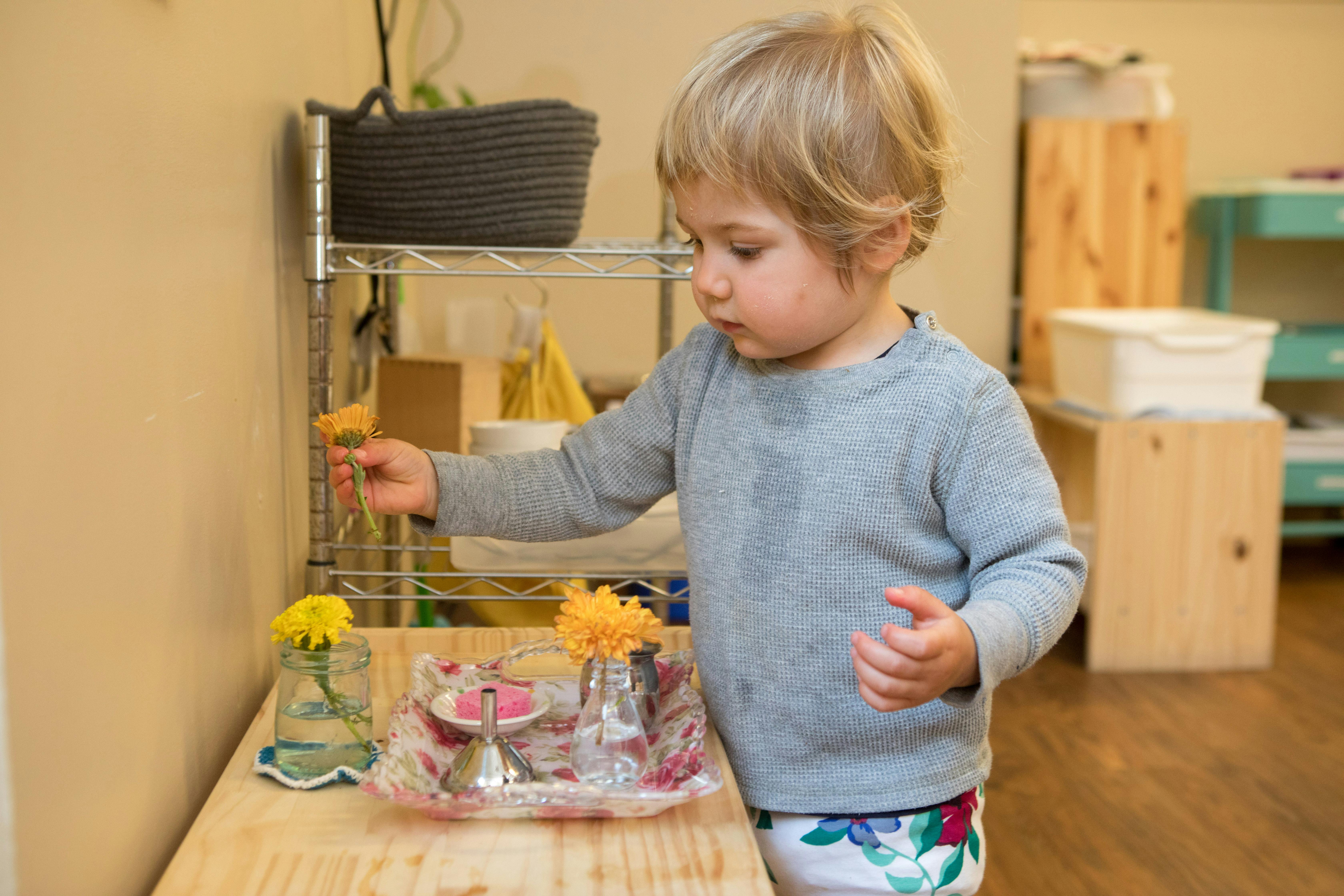 Child arranging flowers in a classroom
