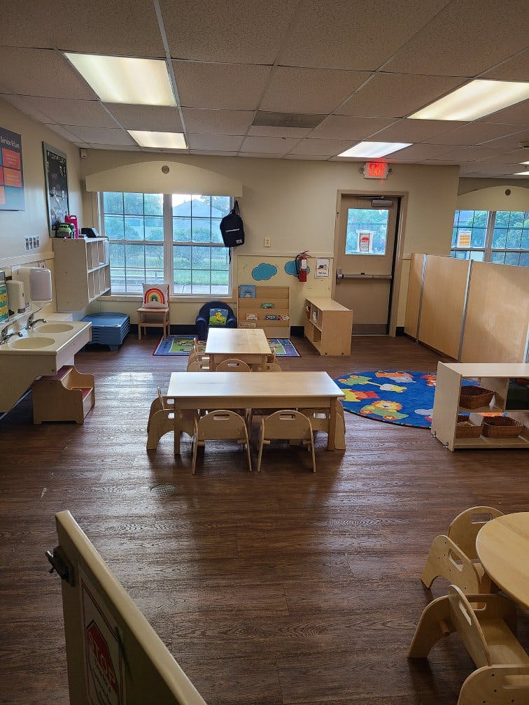Empty classroom with small tables and chairs, sinks, and window