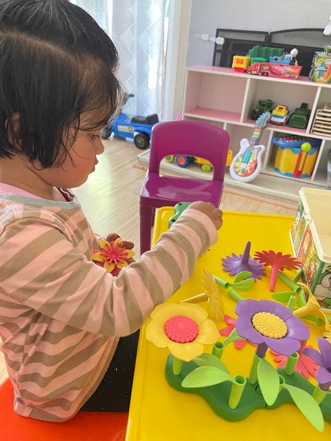 Child playing with flower-shaped toys on a yellow table