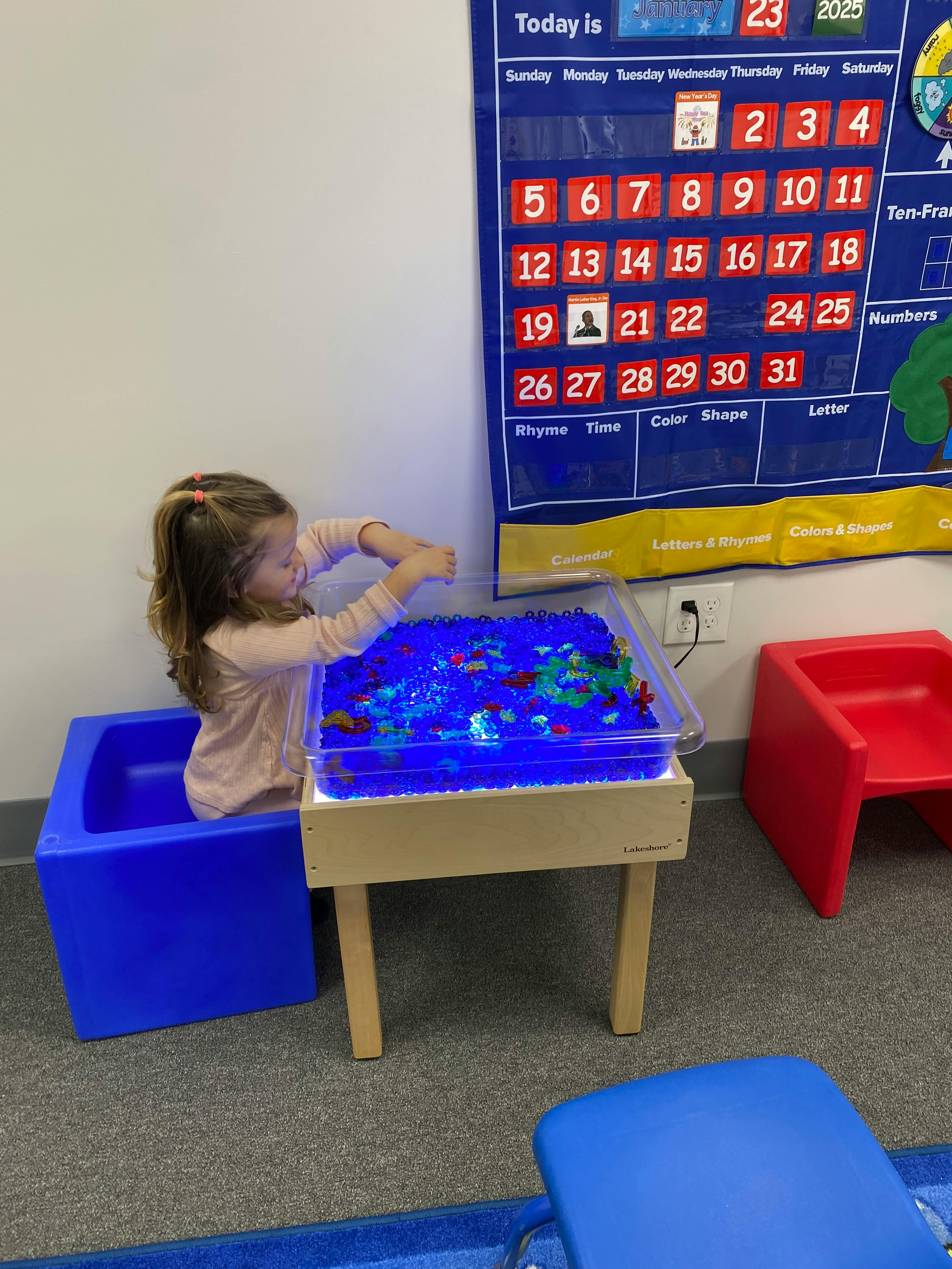 Child playing with blue beads in a sensory bin