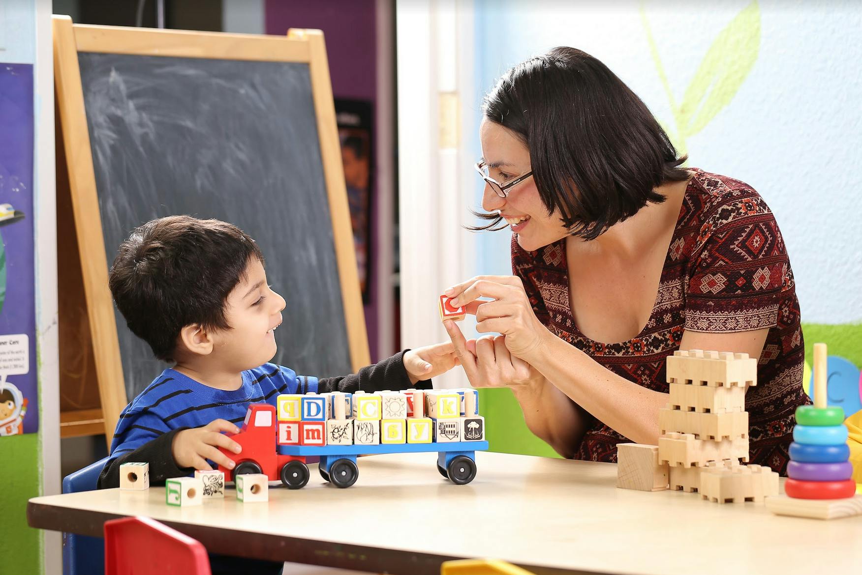 Adult and child playing with toy truck and alphabet blocks