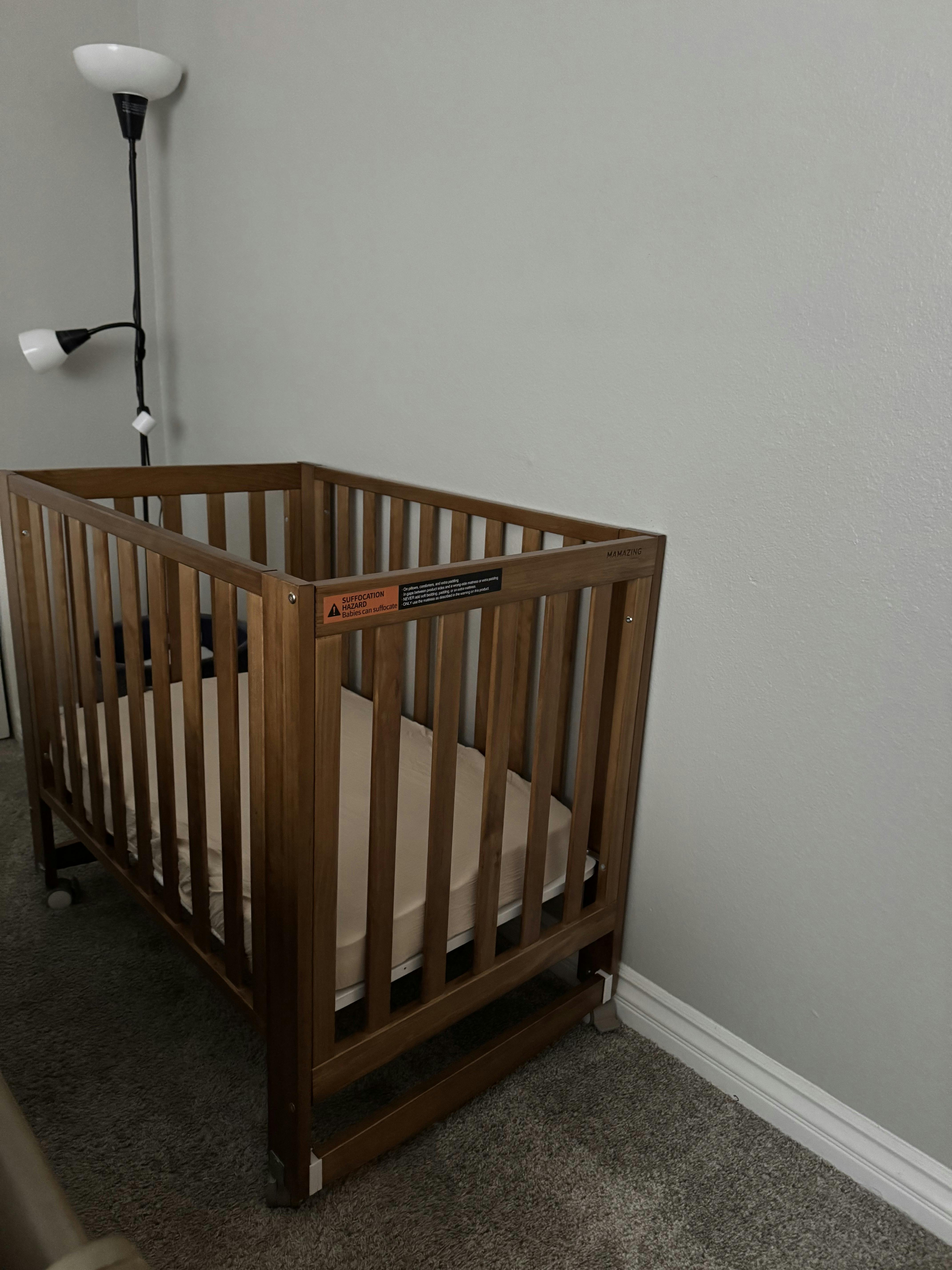 Wooden baby crib with a warning label against a wall