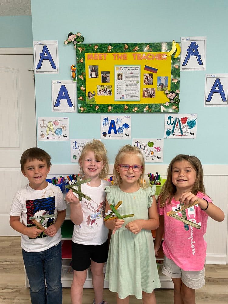 Four children holding craft airplanes in a classroom