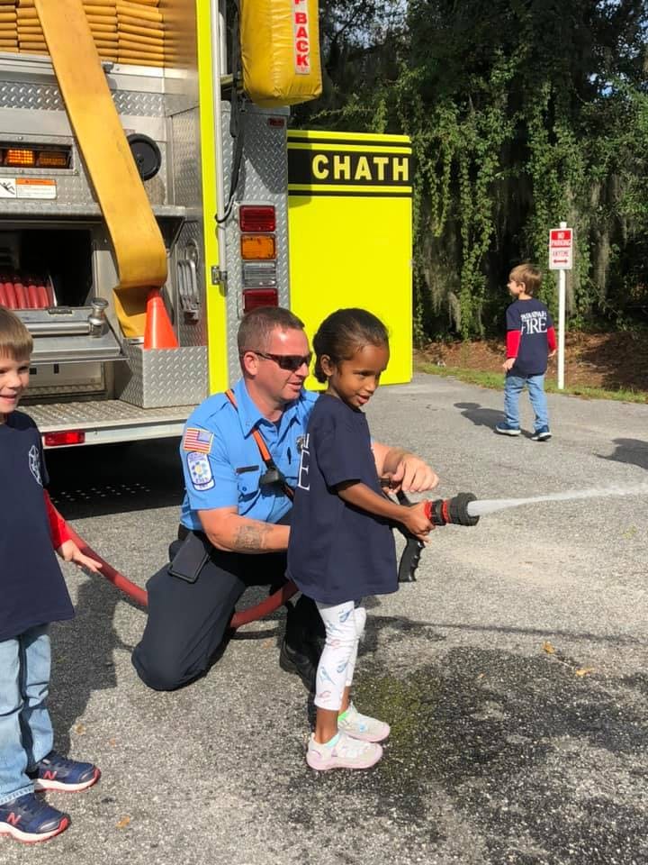 Adult and child holding a fire hose, spraying water