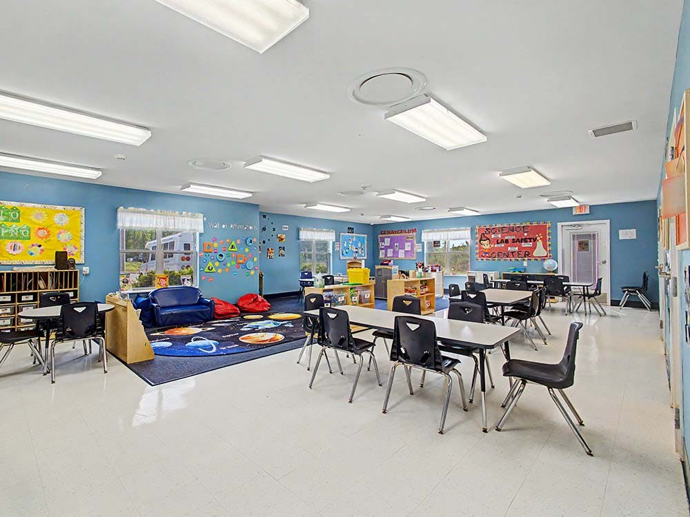 Classroom with tables, chairs, and a blue rug with planets