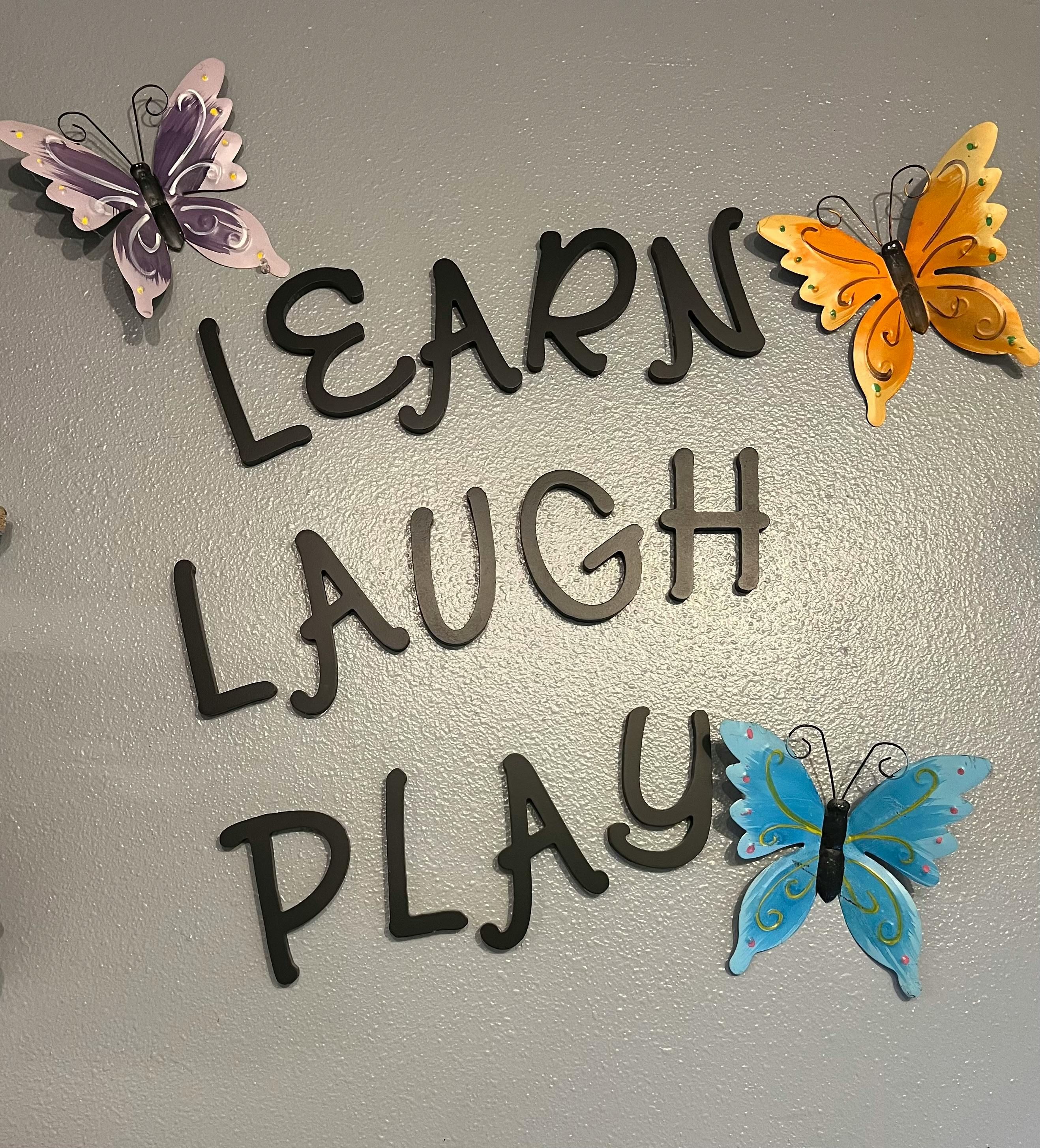 Words "LEARN LAUGH PLAY" with three butterfly decorations