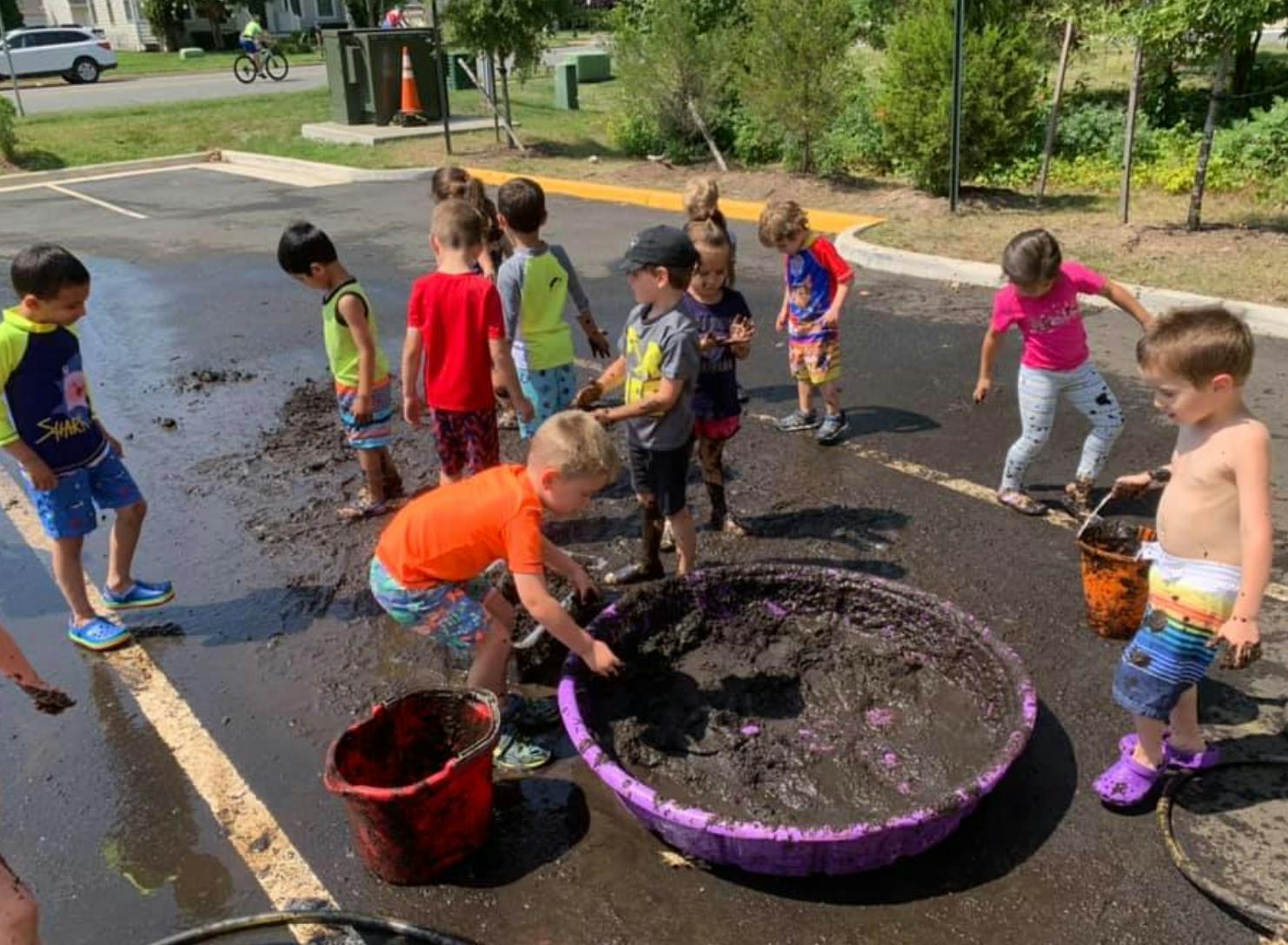 Children playing in mud and water in a parking lot